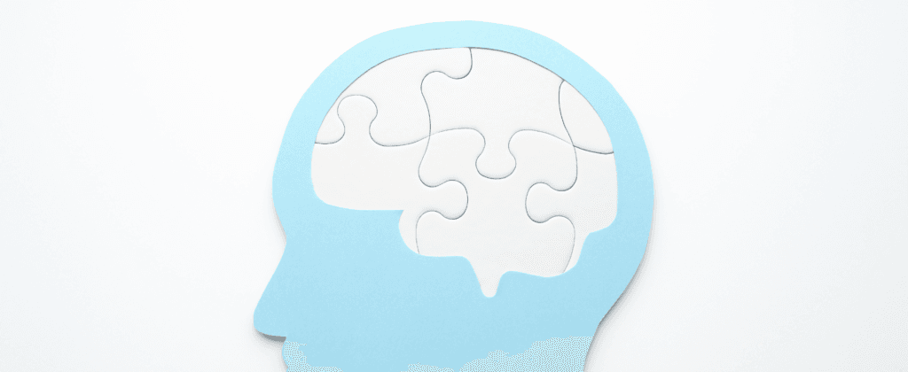 Silhueta de cabeça azul com um cérebro formado por peças de quebra-cabeça brancas, simbolizando a complexidade da saúde mental.